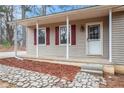 Inviting front porch featuring light siding, red shutters, and stone walkway to entrance at 5700 Tracy Dr, Mableton, GA 30126