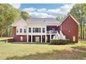 Backyard featuring a sunroom, a walkout basement, a lush green lawn, and many trees surrounding the property at 270 Morrow Rd, Newborn, GA 30056