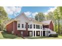 A red brick house boasting an elevated sunroom and a walkout basement is surrounded by a lush green lawn at 270 Morrow Rd, Newborn, GA 30056