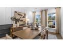 An elegant dining room features wainscotting, neutral decor, and a large window with lots of natural light at 5210 Birch Valley Rd, Cumming, GA 30028