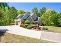 Spacious home featuring a long driveway, three car garage and manicured landscaping at 225 Ansley Close, Roswell, GA 30075