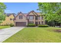 Inviting two-story brick home with a neatly kept lawn, mature trees, and a double-car garage at 2369 Apalachee Crucis Ln, Dacula, GA 30019