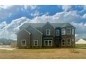 Elegant two-story home with a brick facade and turret-style windows, nestled on a green lawn at 415 Rodeo Dr, Auburn, GA 30102