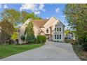 Stucco two-story home with a long driveway, stone accents, lush trees, and landscaping on a sunny day at 422 Laurian Nw Way, Kennesaw, GA 30144