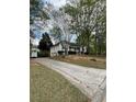 View of the home's exterior with long driveway and landscaping; trees in the background at 30 Dogwood Trl, Dallas, GA 30157