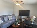 Inviting living room featuring a comfortable gray sofa, ceiling fan, and large-screen television for cozy entertainment at 579 Wexwood Dr, Riverdale, GA 30274