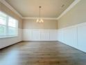 Elegant dining room with wainscoting, hardwood floors, and a stylish chandelier at 5119 Aylesbury Ct, Hoschton, GA 30548