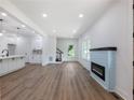 Open-concept living space featuring a modern fireplace, wood-look floors, and a view of the kitchen at 2438 Shadburn Ferry Dr, Buford, GA 30518