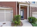 View of front entrance and garage of a brick townhome with manicured landscaping at 4236 Silver Spruce Ln, Smyrna, GA 30080