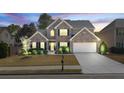 Elegant two-story home with brick facade, complemented by landscape lighting and a manicured lawn at 4215 Evans Farms Dr, Cumming, GA 30040