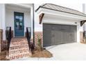 Close up of entrance to new townhome with grey garage and brick steps at 702 Dodd Ln # 159, Buford, GA 30518