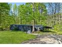 Exterior view of the home with a wooded lot, metal carport and front porch at 3541 Hutcheson Ferry Rd, Whitesburg, GA 30185