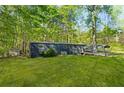 Exterior view of the home with a large grass lawn and wooded lot at 3541 Hutcheson Ferry Rd, Whitesburg, GA 30185