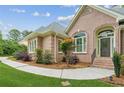 Close up showing a brick home's arched entryway, manicured garden beds, and pristine lawn at 2060 Pate Ridge Dr, Loganville, GA 30052