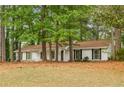 Ranch-style home with white siding, black shutters, and mature trees on a grassy lot at 2694 Hickory Valley Dr, Snellville, GA 30078