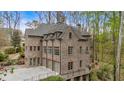 Brick home featuring multiple garage spaces, balconies, and lush greenery at 115 Mount Paran Rdg, Atlanta, GA 30327