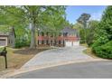 Attractive brick home featuring a spacious driveway and a two-car garage, surrounded by mature trees at 3130 Crestmont Nw Way, Kennesaw, GA 30152