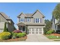 Beautiful gray two-story home with well-manicured landscaping, a two-car garage, and a welcoming facade at 8385 E Village School E Dr, Cumming, GA 30041