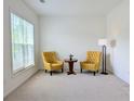 Bright living room with two chairs, small round wood table and a floor lamp with a window view at 580 Hammersmith Dr, Suwanee, GA 30024