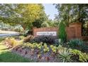 Community entrance sign with brick columns surrounded by lush greenery and flowers at 818 Prada Ct, Lawrenceville, GA 30043