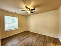 An empty bedroom featuring wood floors, tan walls, and natural light from the window at 645 Crossbridge Aly, Johns Creek, GA 30022