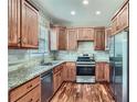 Well-lit kitchen showcasing wooden cabinets, granite countertops, stainless steel appliances, and elegant hardwood floors at 3765 Clear Lake Nw Way, Acworth, GA 30101