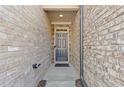 Covered entryway featuring a modern gray front door and brick walls at 8335 Village Pl, Suwanee, GA 30024