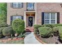 Inviting front entrance with a black door framed by manicured shrubs at 2822 Savannah Walk Cv, Suwanee, GA 30024