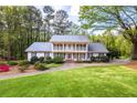 Inviting two-story home boasts a lush green lawn and a charming front porch in a serene setting at 1800 East Gate Dr, Smoke Rise, GA 30087