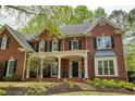 Attractive red brick home with a covered porch, steps to the front door and manicured landscaping at 325 N Saint Phillip Ln, Alpharetta, GA 30022