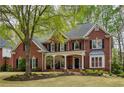 Charming red brick home with a covered porch, manicured lawn, and black shutters at 325 N Saint Phillip Ln, Alpharetta, GA 30022