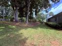 Backyard features a lush lawn, mature trees, and a brick retaining wall at 1552 Longwood Dr, Lawrenceville, GA 30043