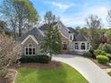 Charming home featuring manicured lawn, stone accents, gray stucco, and a curved driveway at 315 Stanyan Pl, Alpharetta, GA 30022