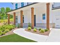 Inviting front porch with wooden columns, gray brick accents and manicured landscaping at 399 Tillman Pass, Woodstock, GA 30188