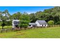 Charming white farmhouse with black roof, surrounded by vibrant green lawn and a rustic wooden fence at 85 Carroll Slough Rd, Kingston, GA 30145