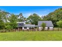 Beautiful modern farmhouse with black metal roof and white siding surrounded by lush greenery and a wooden fence at 85 Carroll Slough Rd, Kingston, GA 30145