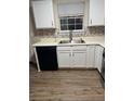 Kitchen featuring white cabinets, stainless steel sink, black dishwasher and neutral backsplash at 6715 Roscommon Dr, Austell, GA 30168