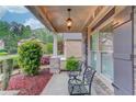 Cozy front porch with stone accents, seating, and views of landscaped front yard at 1633 Park Hollow Ln, Lawrenceville, GA 30043