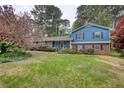 Charming two-story home with a brick facade, blue siding, and a well-manicured lawn with mature trees at 493 James Street Sw, Lilburn, GA 30047