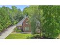 Charming red brick home with lush landscaping and a long driveway nestled among mature trees at 1418 Brighton Pl, Loganville, GA 30052