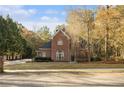 Charming brick home featuring a well-manicured lawn and mature trees under a bright blue sky at 1418 Brighton Pl, Loganville, GA 30052