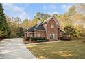 A stunning brick home features a manicured lawn, a driveway, and lush trees at 1418 Brighton Pl, Loganville, GA 30052
