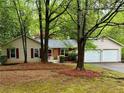 A view of the home's facade, including the front door, red shutters, landscaping, and two car garage at 455 Tyson Cir, Roswell, GA 30076