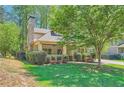 Inviting home exterior with a stone chimney, covered porch, manicured landscaping and lush green lawn at 1714 Parkhill Dr, Decatur, GA 30032