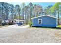 Exterior shot showing a gravel driveway, white house with front porch, and blue house at 5955 Kemp Dr, Acworth, GA 30102