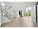 Bright living room featuring a staircase, hardwood floors, a fireplace, and large windows at 155 Westbrook St, Buford, GA 30518