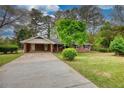 Brick home featuring a spacious driveway, carport, and lush landscaping at 1311 Maple Street Se, Conyers, GA 30013
