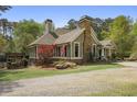 Beautiful home exterior with a stone chimney, well-maintained lawn, and a picturesque landscape at 5655 Mccoy Rd Nw, Acworth, GA 30101