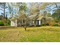 Cozy single-story house with a manicured lawn, set among blossoming trees, and featuring gray siding and dark shutters at 2867 Payton Ne Rd, Atlanta, GA 30345