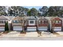 Charming townhomes with attached garages and brick and stone exteriors line a cozy neighborhood street at 545 Woodland Park Ter, Lawrenceville, GA 30043